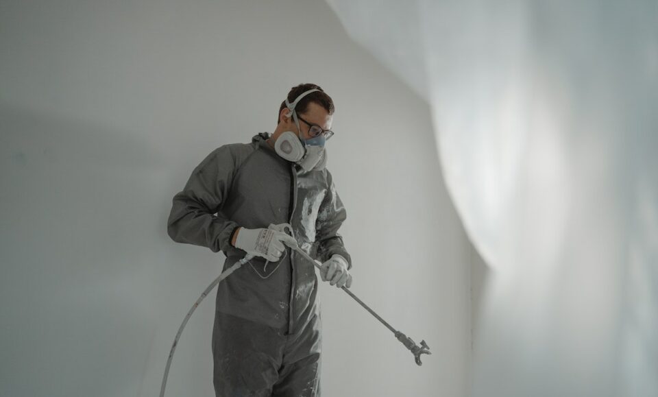 A Man in Gray Suit Painting a House