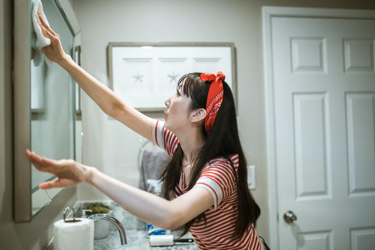 Woman in Red and White Stripe Shirt Wiping the Mirror